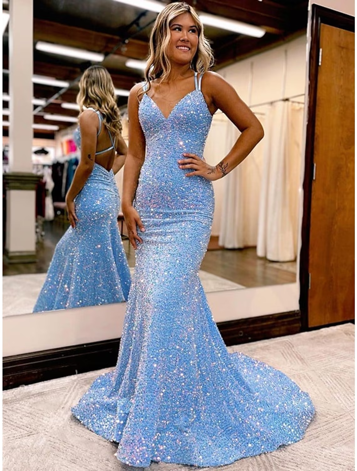 Woman wearing a glamorous dark velvet sequin sheath prom dress with a V-neck and sweep train.