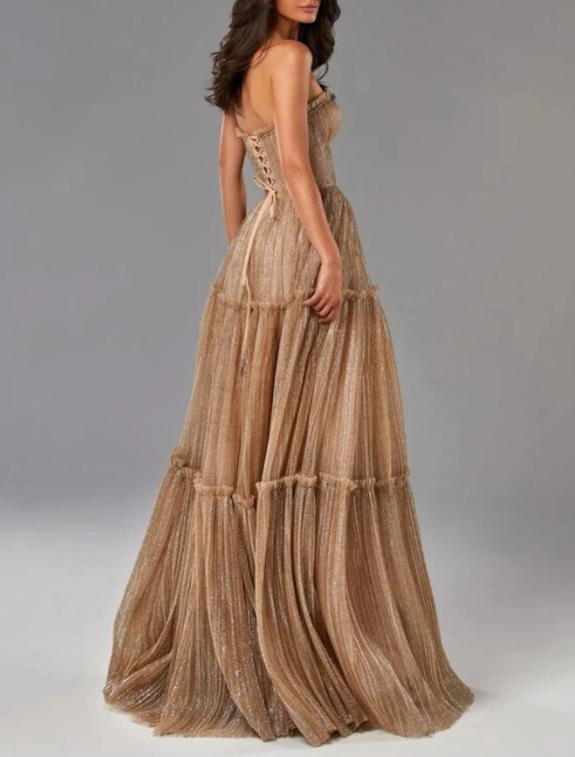 Back view of a woman in a glittering floor-length A-line gown.
