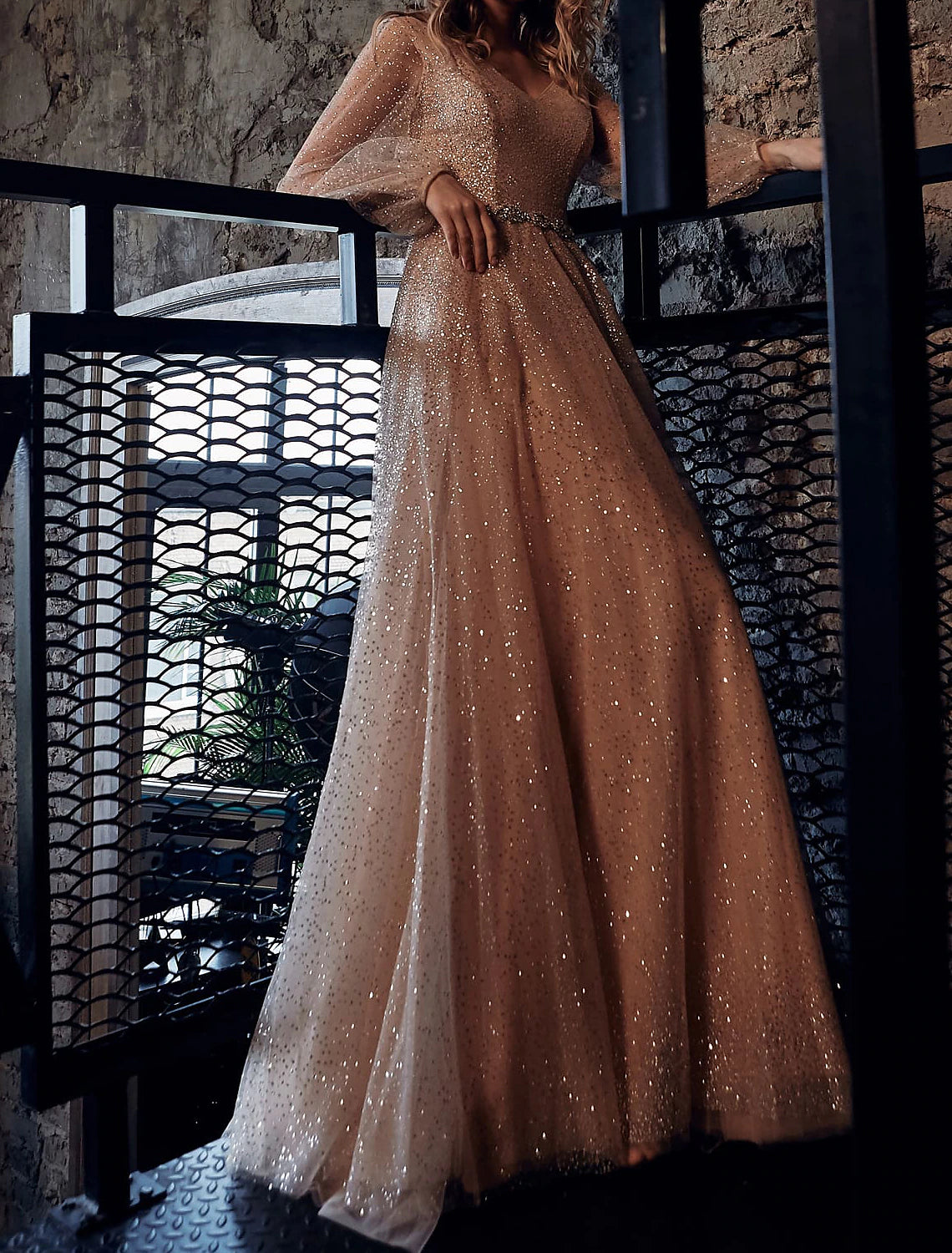 Woman wearing a glittering A-line V-neck long sleeve maxi prom dress.