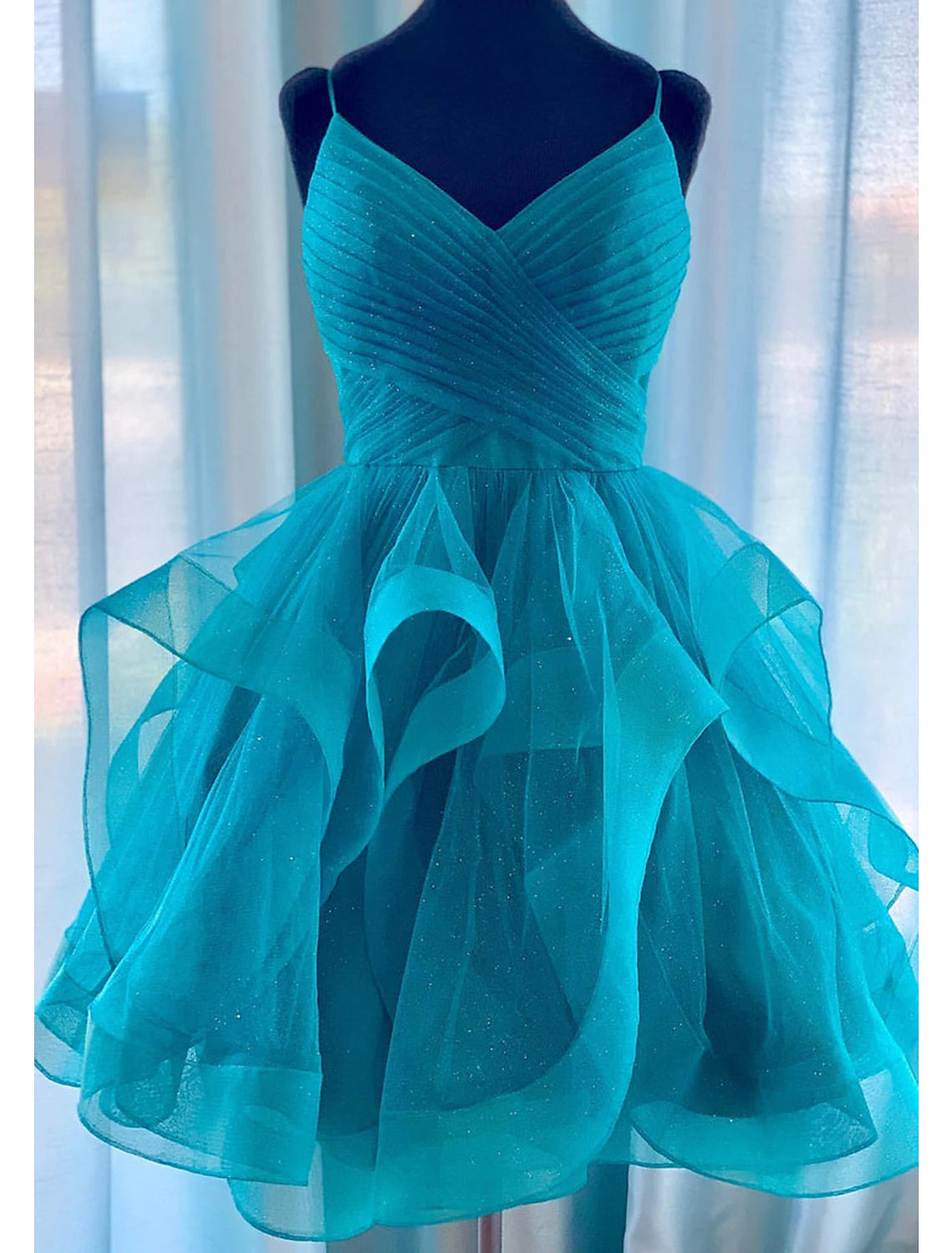 Model wearing a glittering mini ball gown homecoming dress with spaghetti straps.