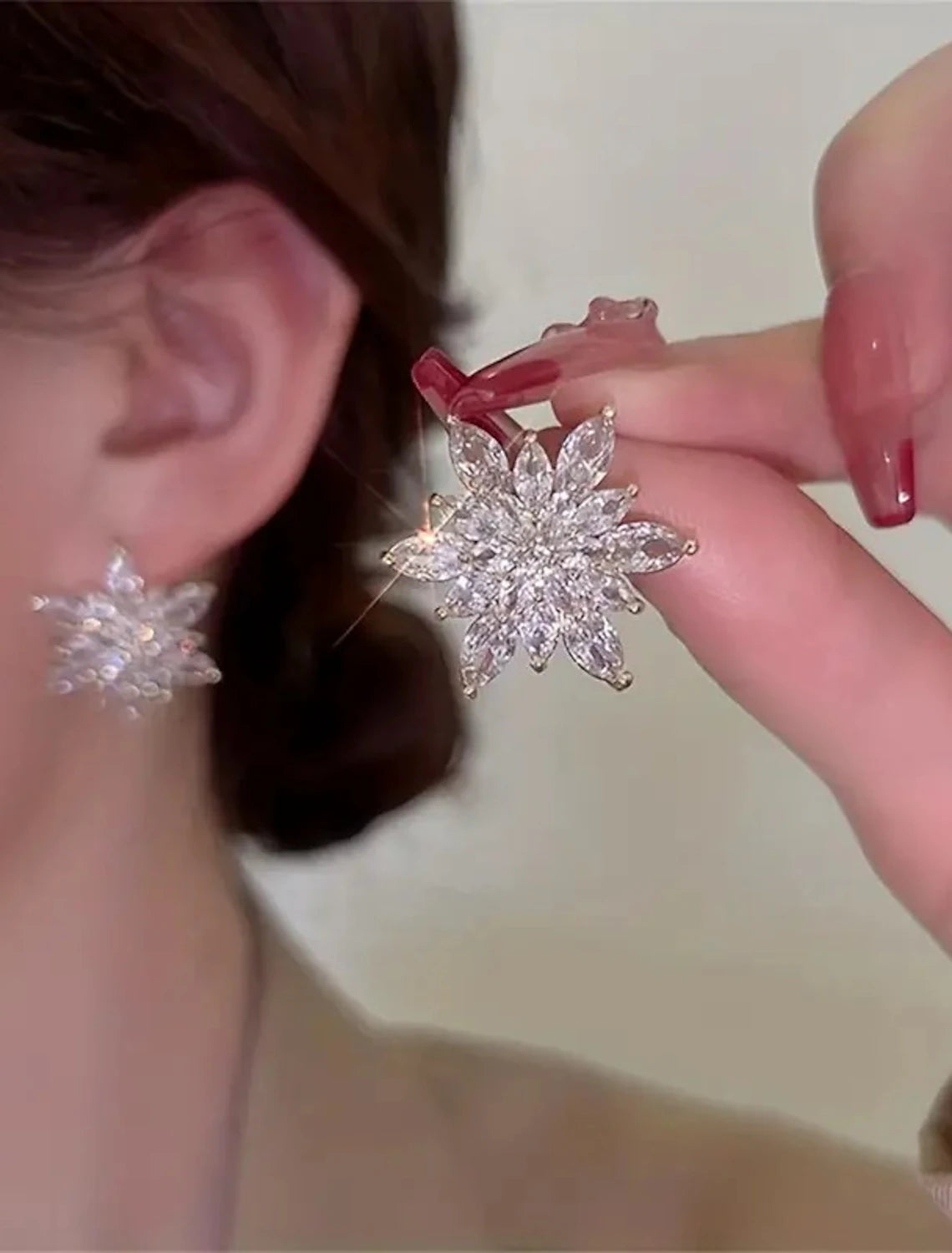 Golden flower stud earring worn on an ear.
