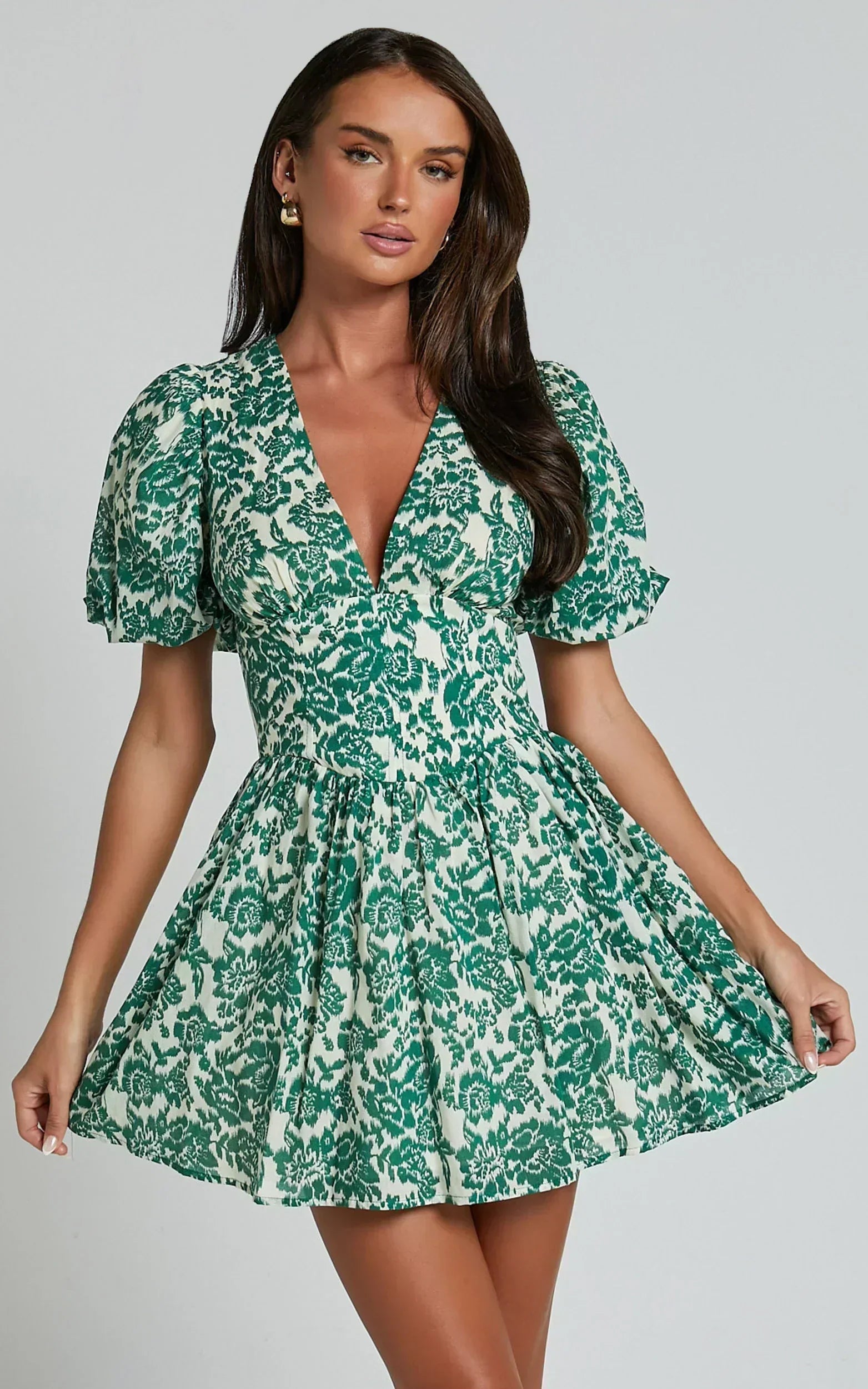 Woman wearing a green floral print puff sleeve V-neck mini homecoming dress.