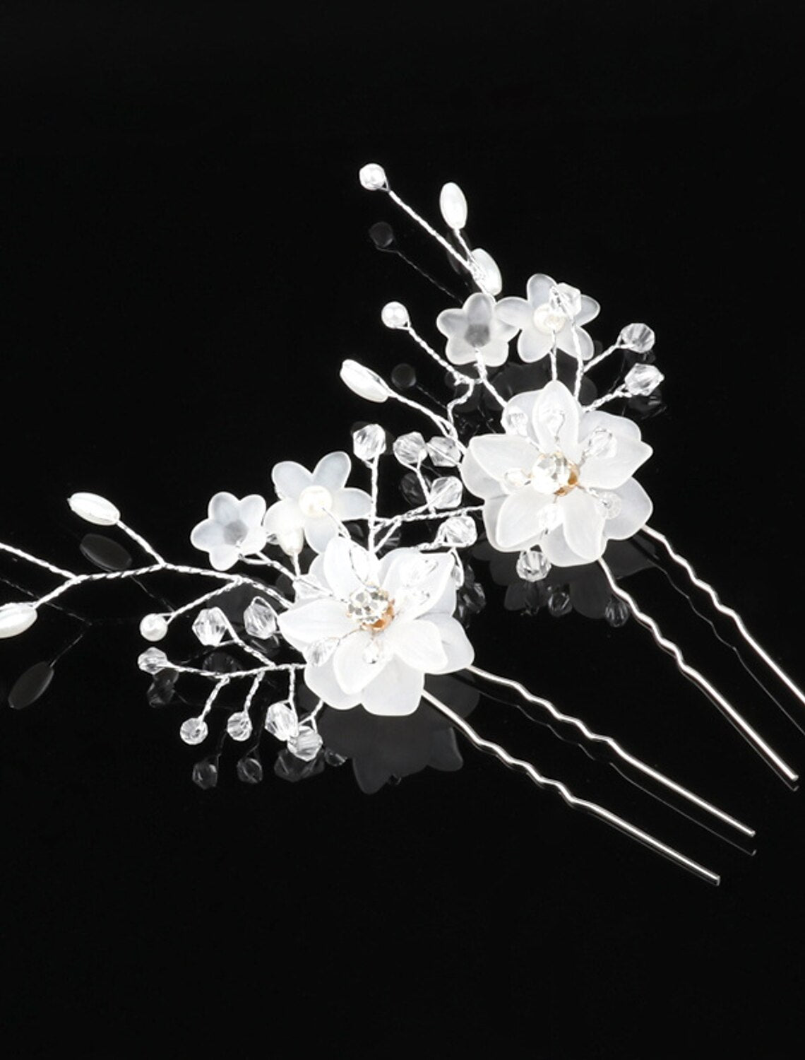 Delicate handmade floral hair accessory with white flowers and green leaves.