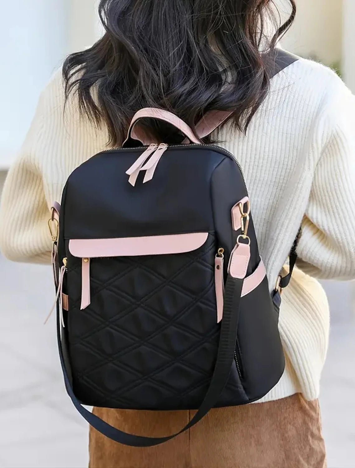 Black anti-theft backpack worn by a woman.