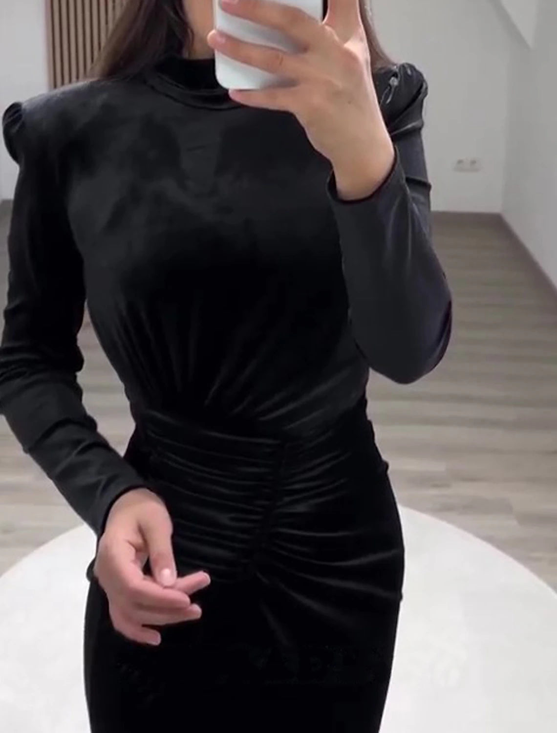 Side view of a woman in a black velvet high-neck long-sleeve sheath gown.