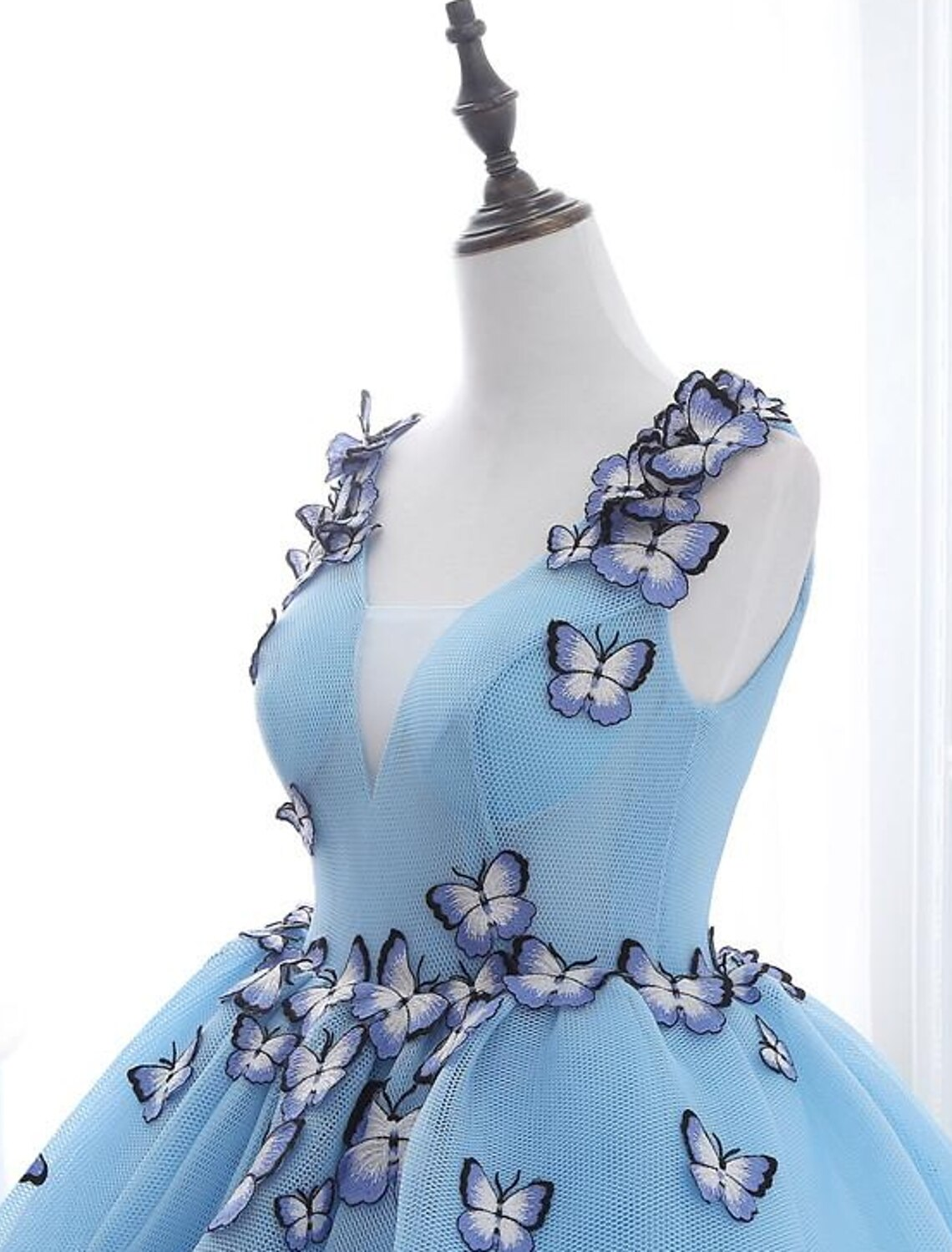 Side profile of a V-neck ball gown prom dress with intricate pleats.