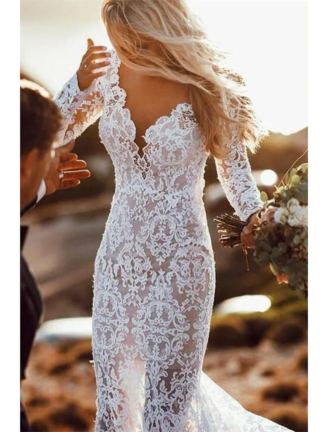 Full view of an elegant mermaid V-neck wedding dress with intricate appliques, long sleeves, and a flowing court train.