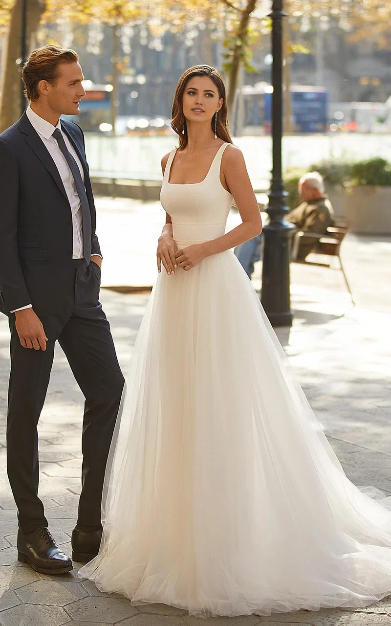 A-line minimalist square neck tulle wedding dress with a sweep train, shown from the front.