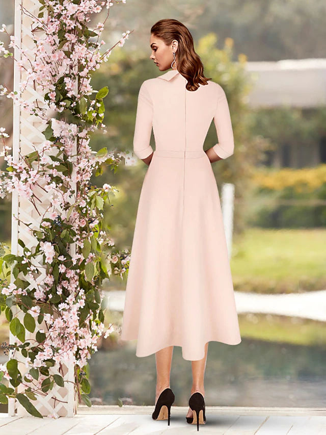 Tea length minimalist mother of the bride dress in solid satin with subtle pleats.