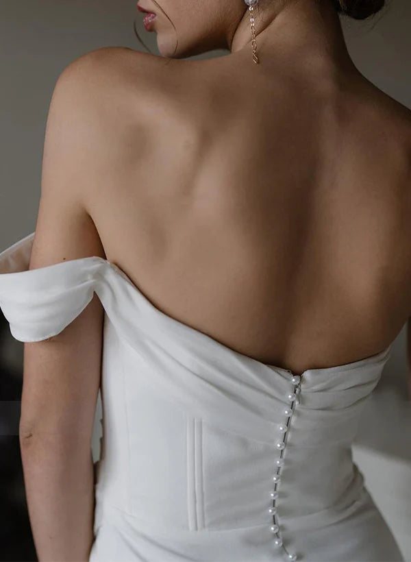 Side view of a bride in a sheath satin gown, highlighting the one-shoulder design and high slit.