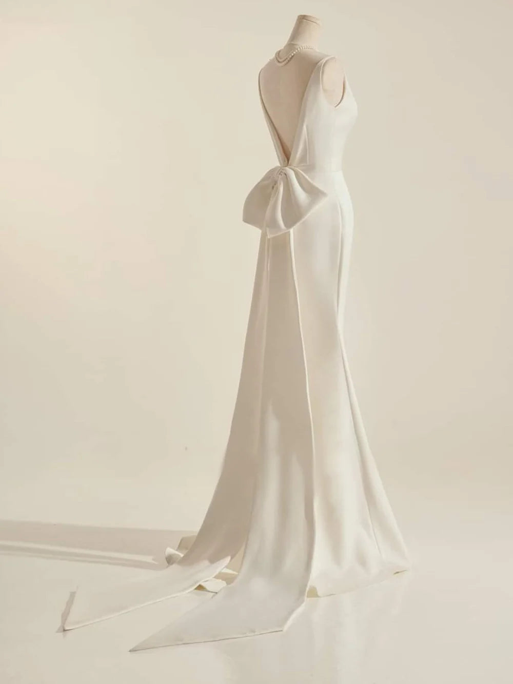 Back view of a simple mermaid wedding dress, highlighting the sleek silhouette and bow accent.