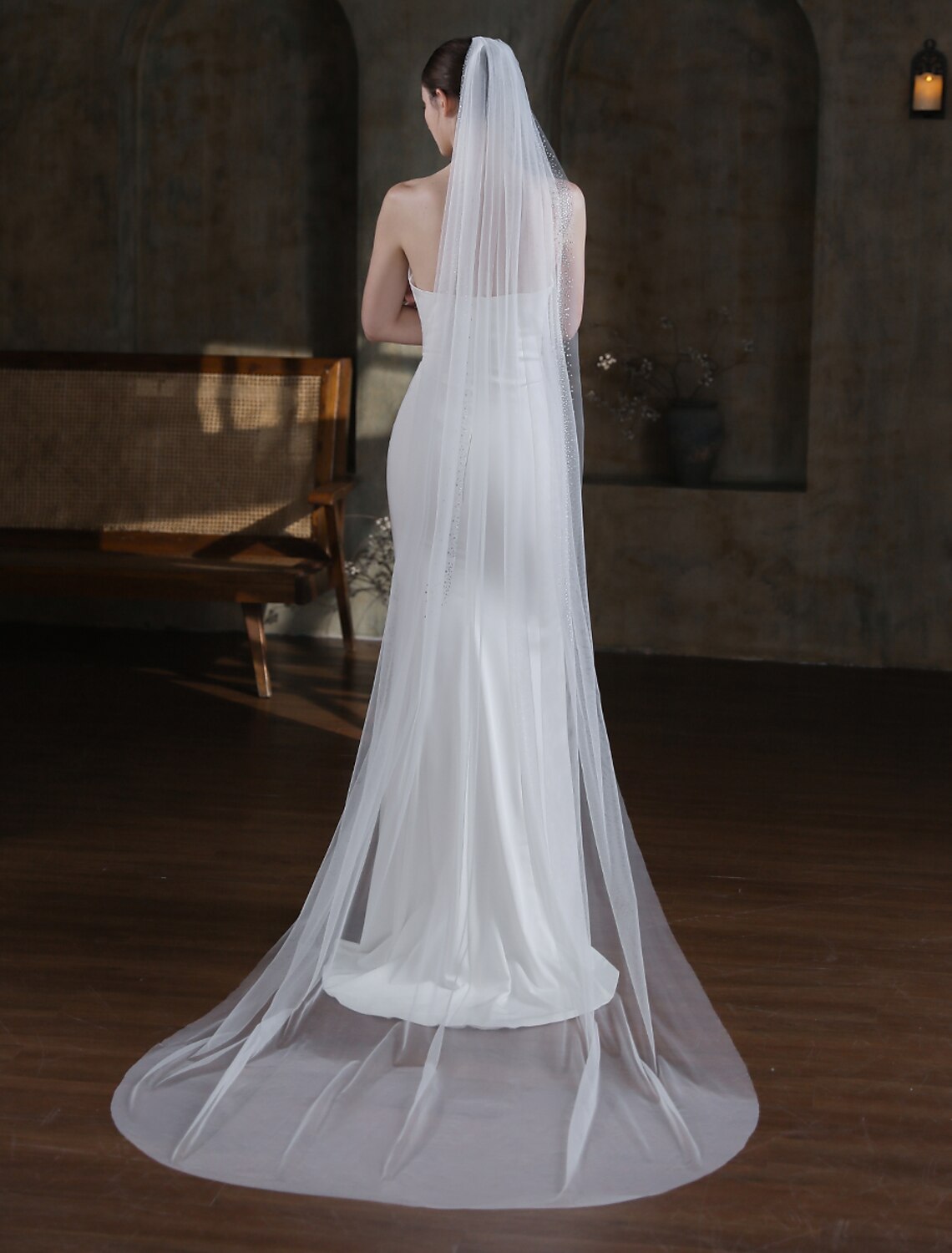 Close-up of a bride's back, showcasing the sparkling glitter tulle of a cathedral wedding veil.