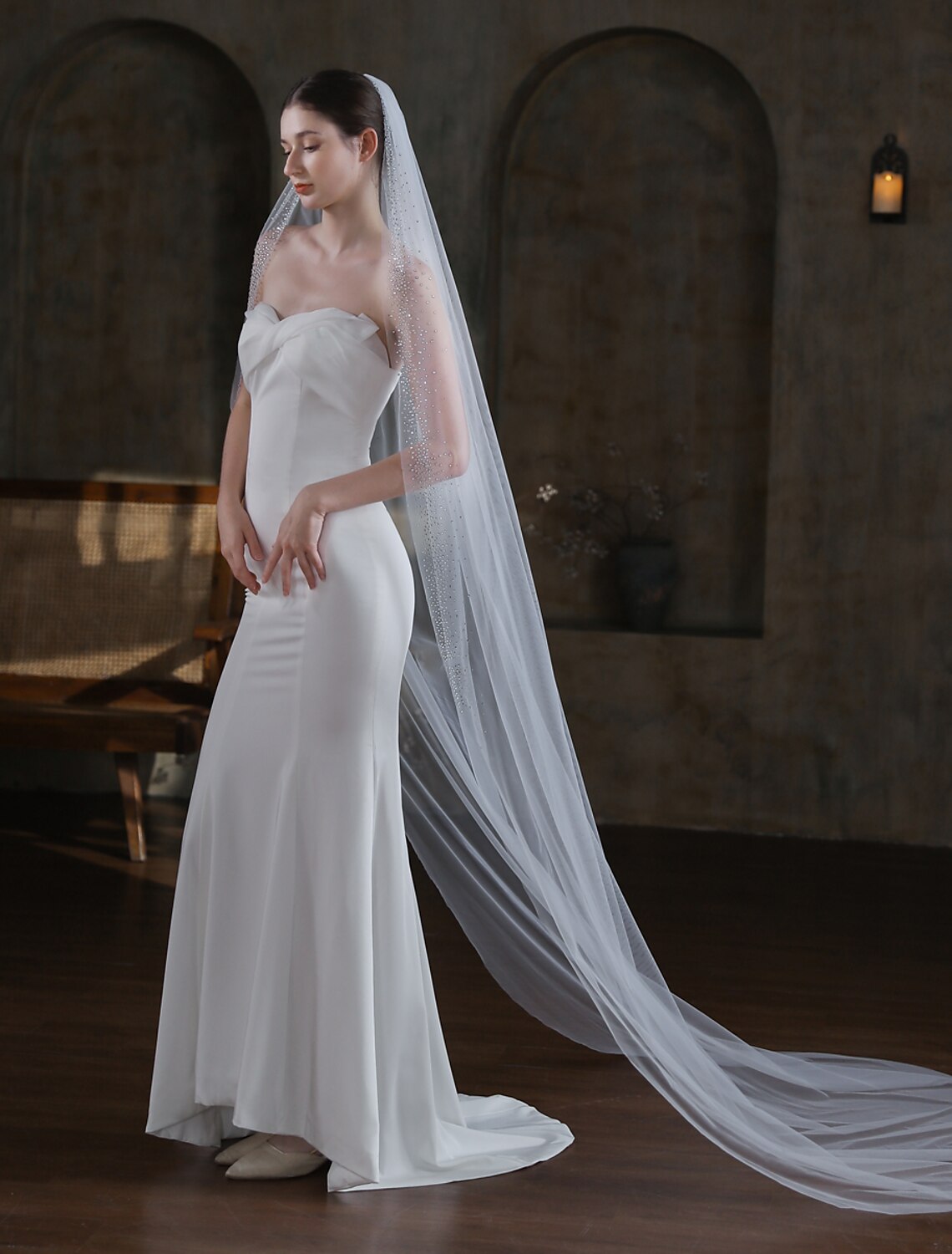Side view of a bride wearing a shimmering one-tier cathedral wedding veil.