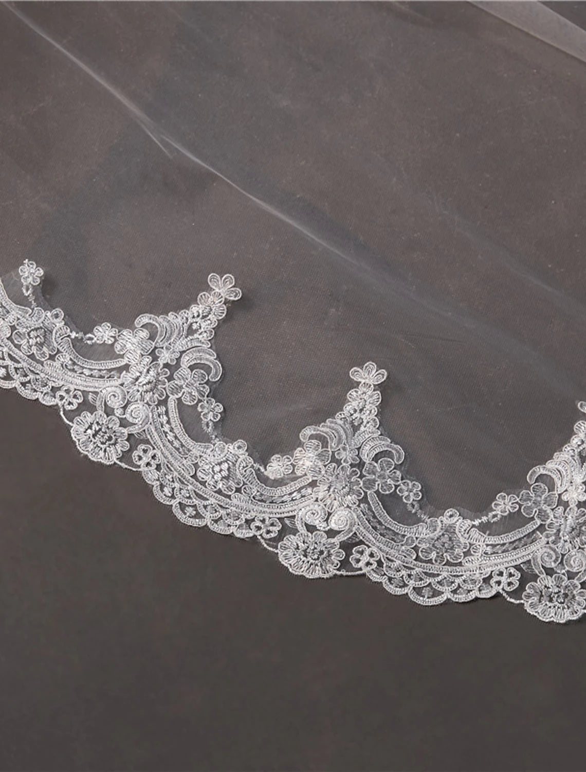 Elegant one-tier wedding veil with appliques draped for display.