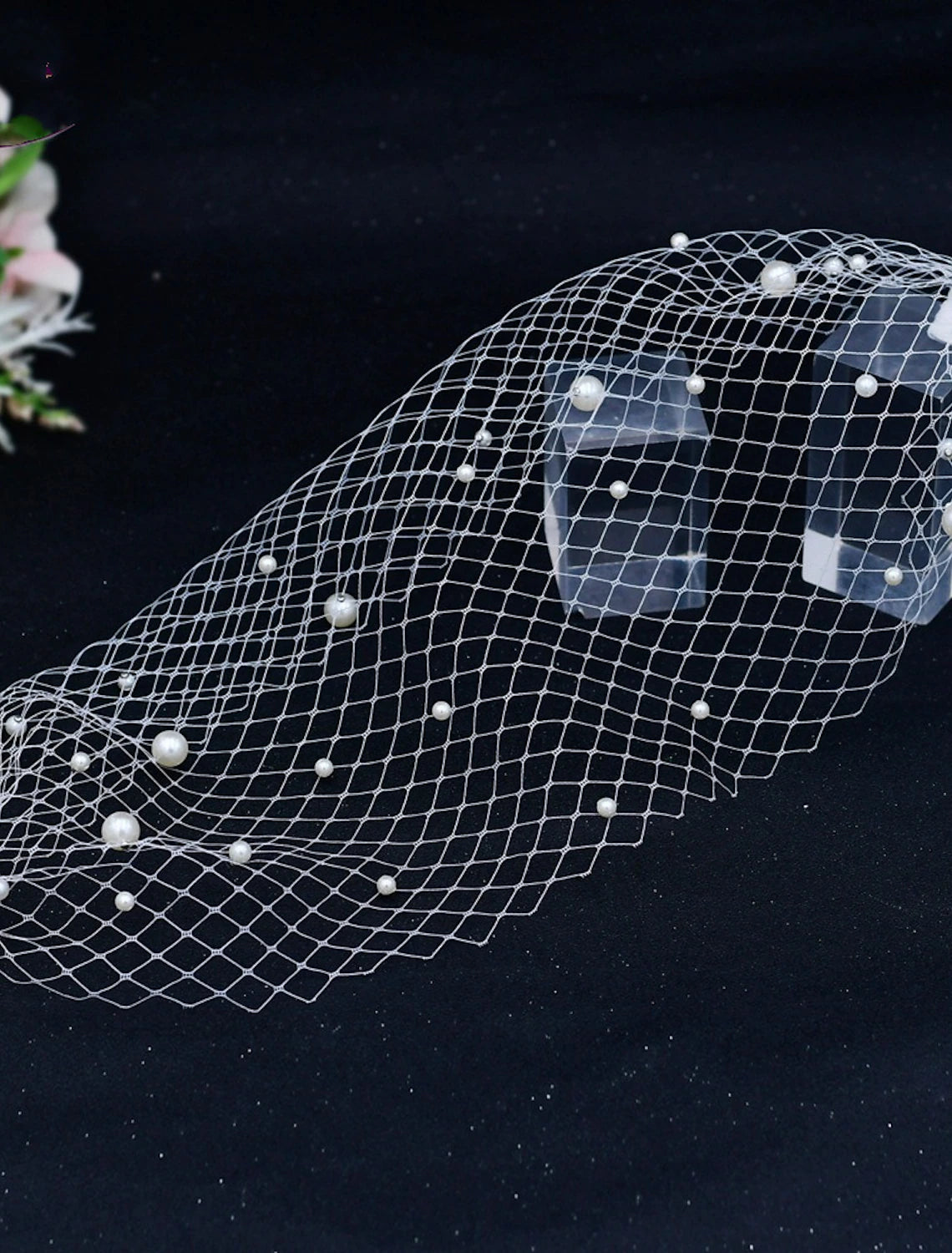 Close-up of faux pearls on a delicate tulle blusher wedding veil.