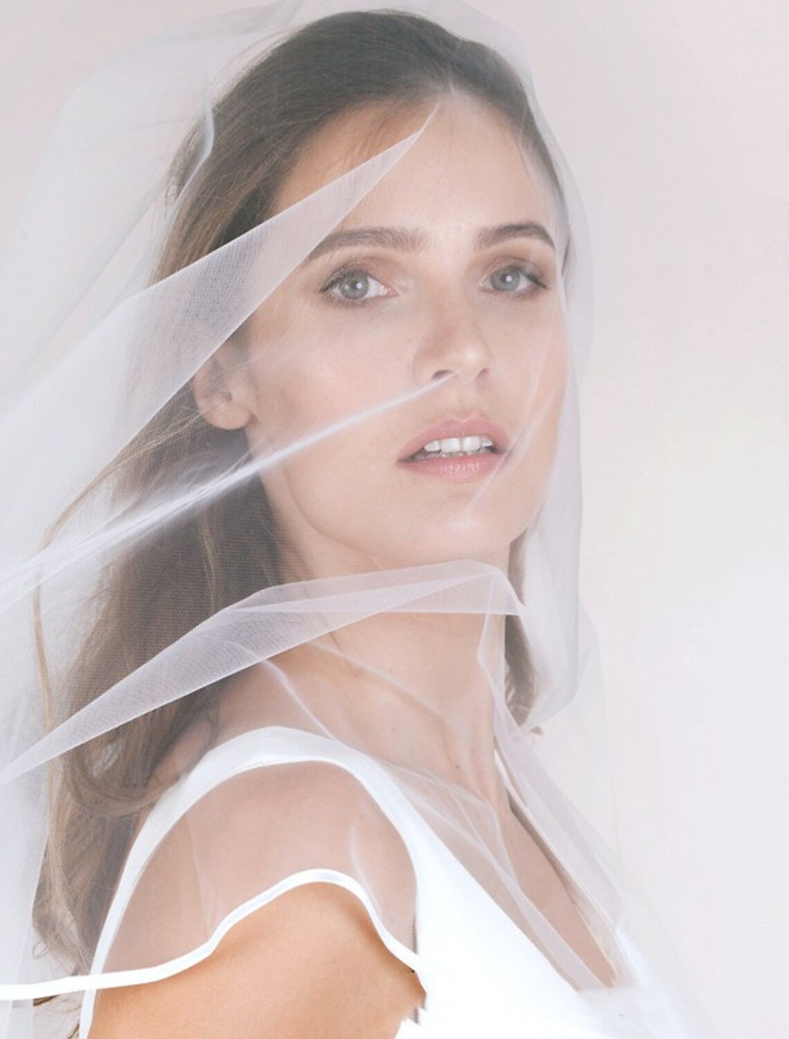 Side profile of a bride showcasing a simple blusher veil.