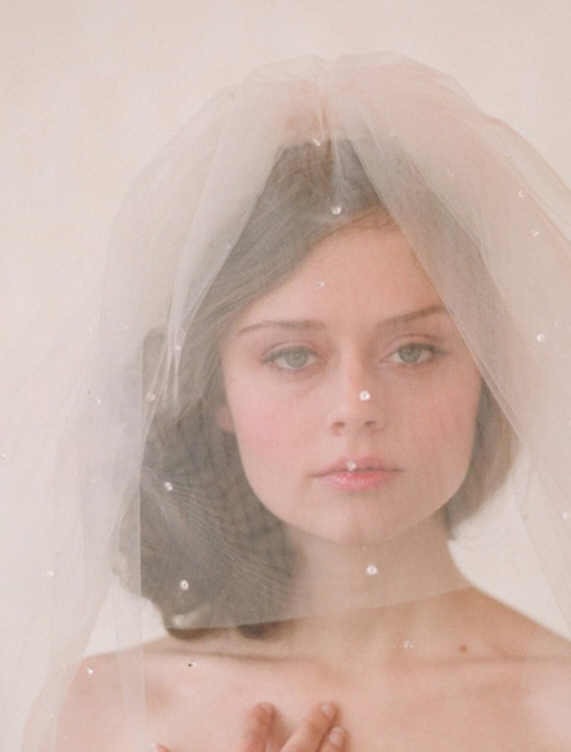 A bride wearing a one-tier 60cm tulle wedding veil with rhinestone and crystal embellishments.