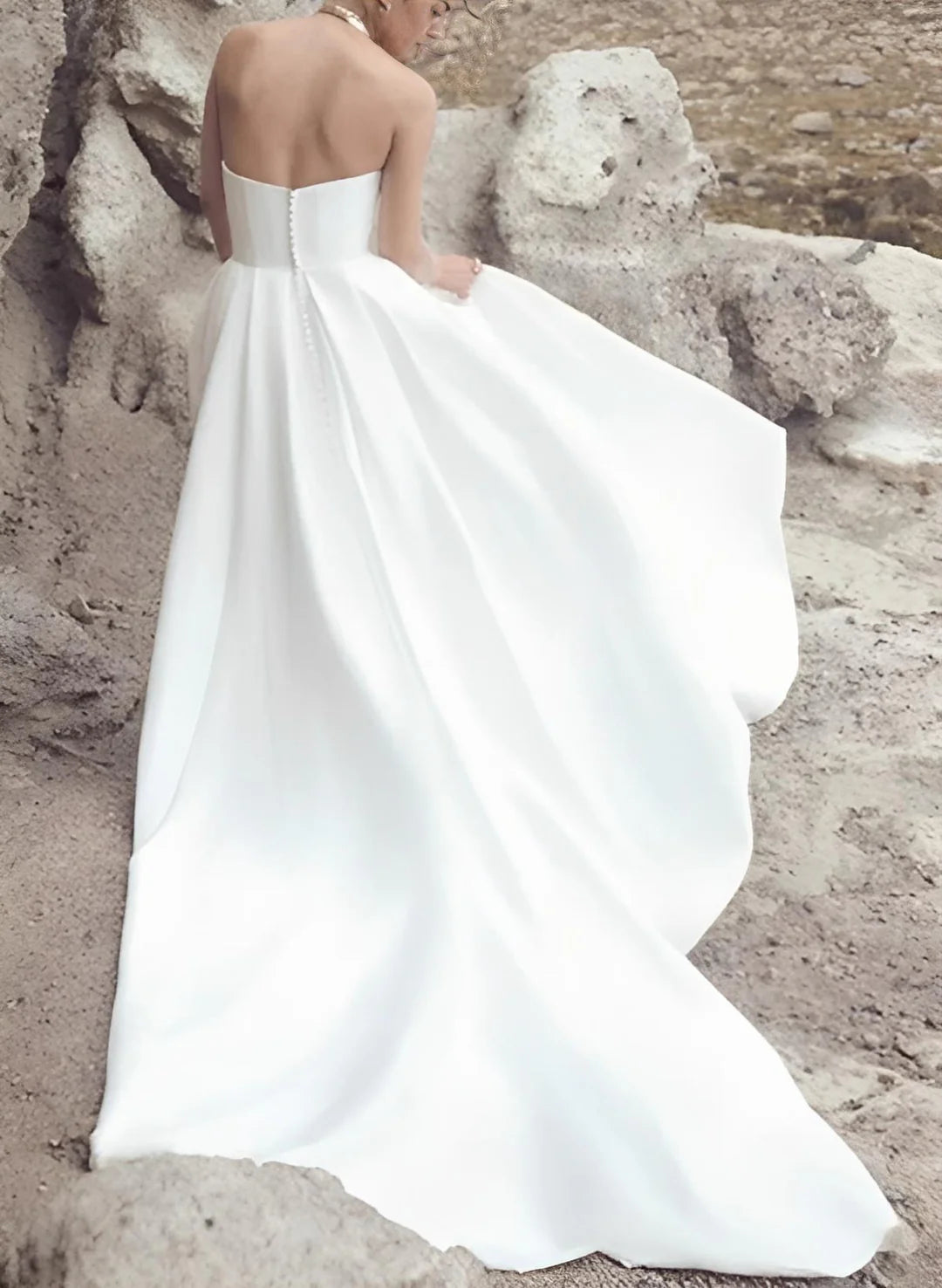 Plus size model in a white strapless A-line wedding dress, side view.