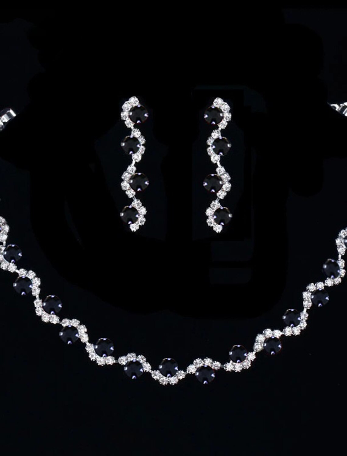 Close-up of rhinestone tennis chain necklace and matching earrings.