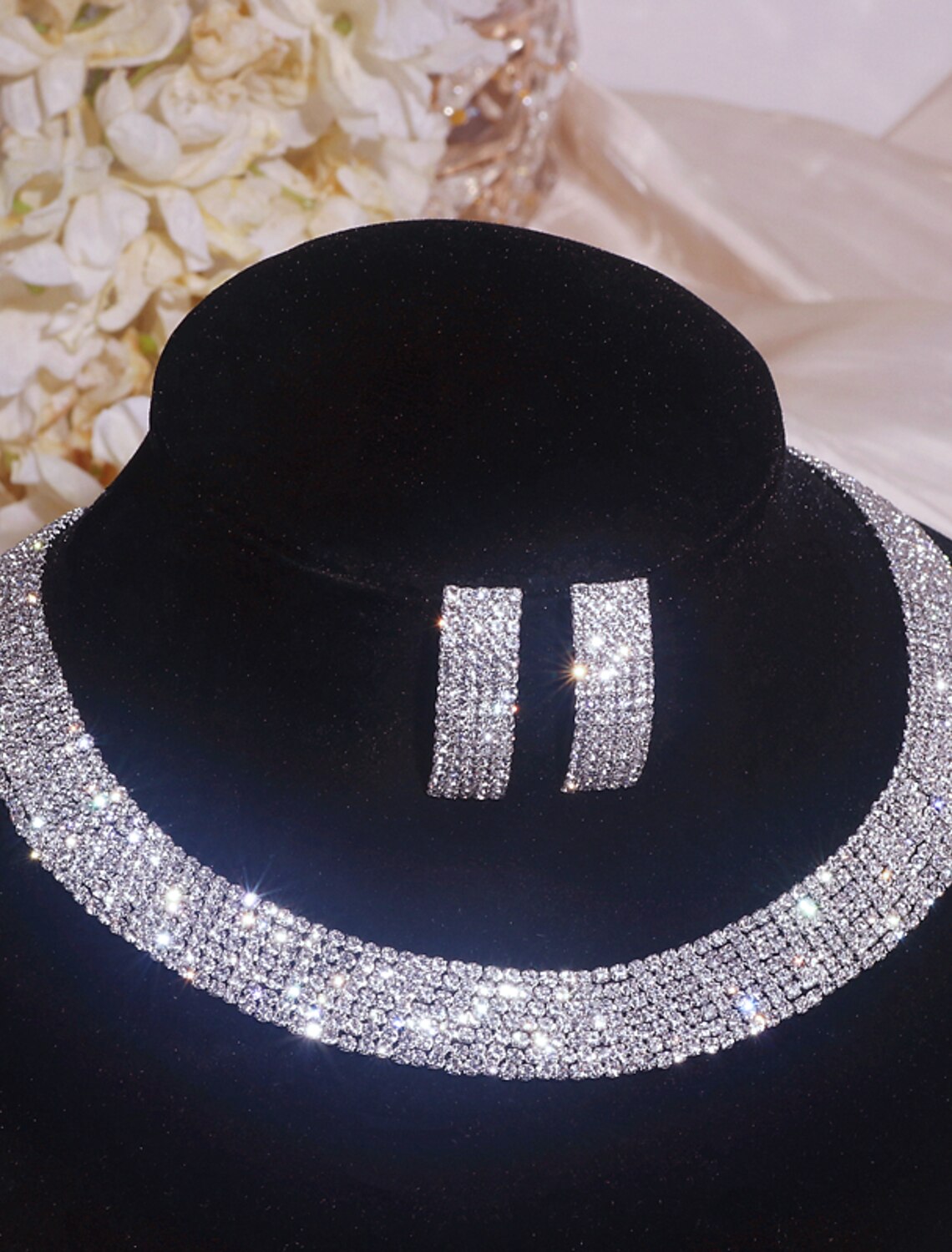 Woman wearing a sparkling rhinestone necklace and matching earrings.