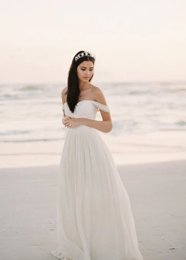 Side view of A-line chiffon wedding dress with off-shoulder neckline.