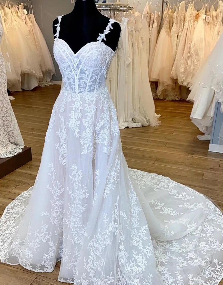 A-Line wedding dress with spaghetti straps and appliques, featuring a court train.