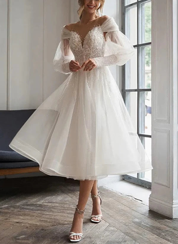 A-line sweetheart wedding dress with lace appliques and long sleeves.