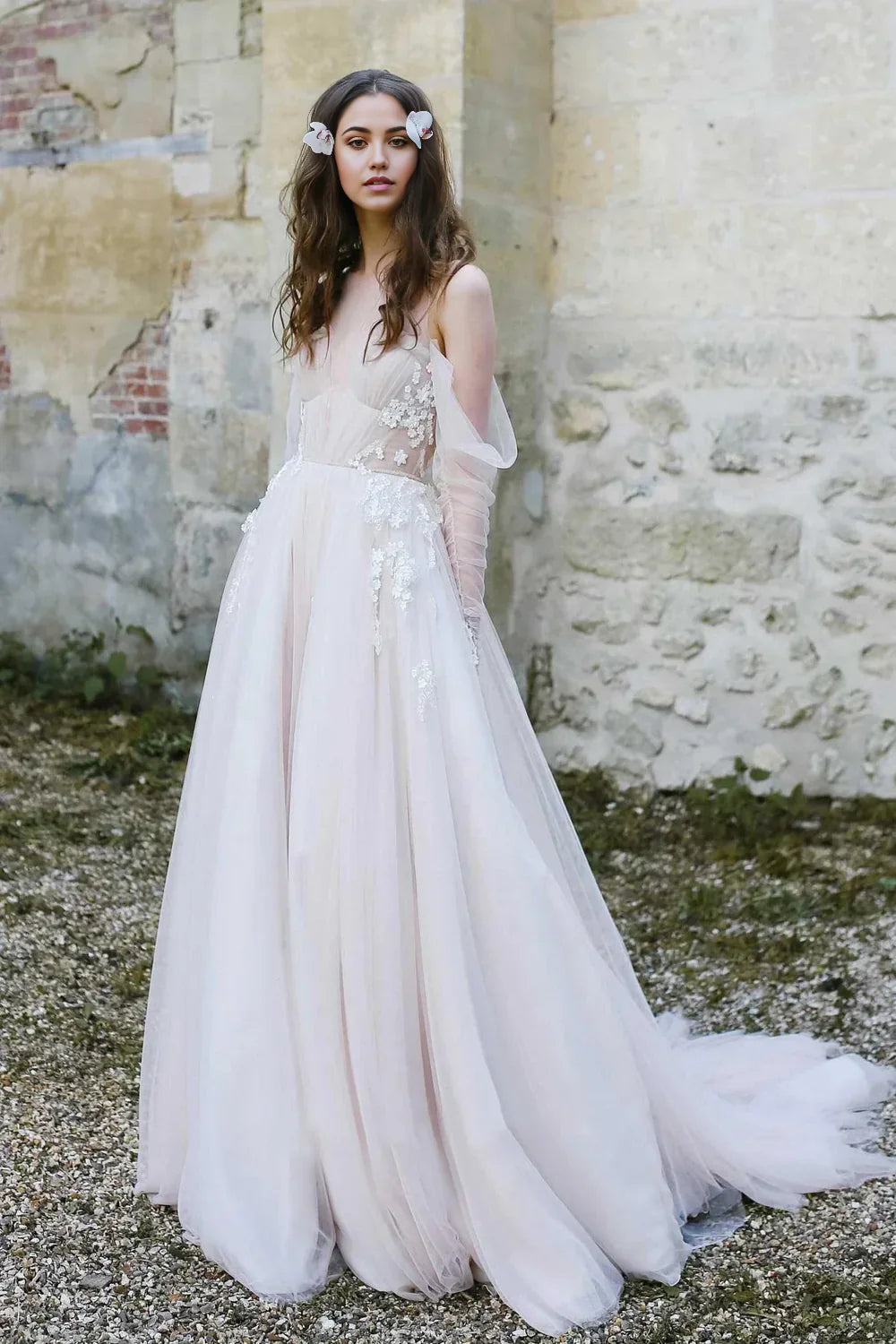 Bride wearing A-line off-shoulder wedding dress with floral appliques and sweep train.