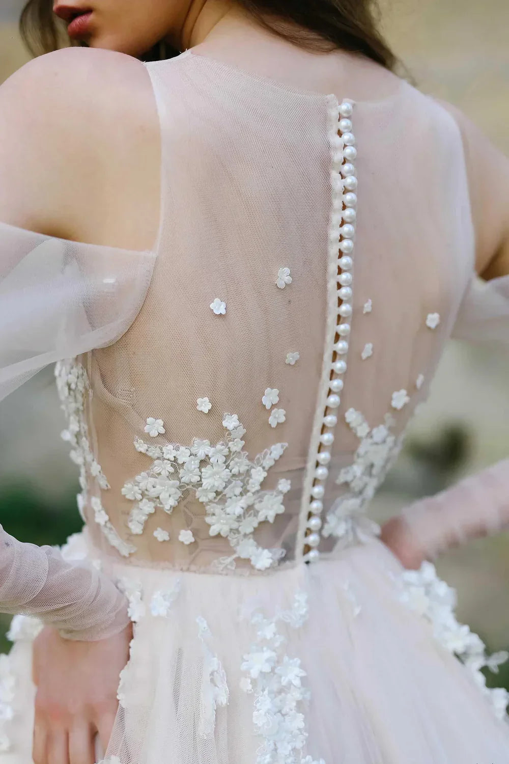 Back view of A-line off-shoulder wedding gown featuring illusion tulle and floral details.