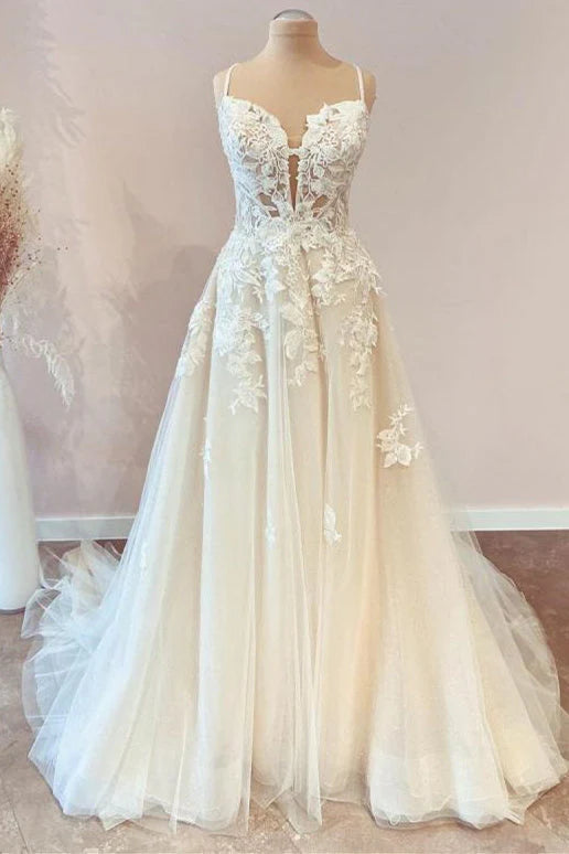 Front view of an A-line tulle wedding dress with spaghetti straps, V-neck, and lace appliques.