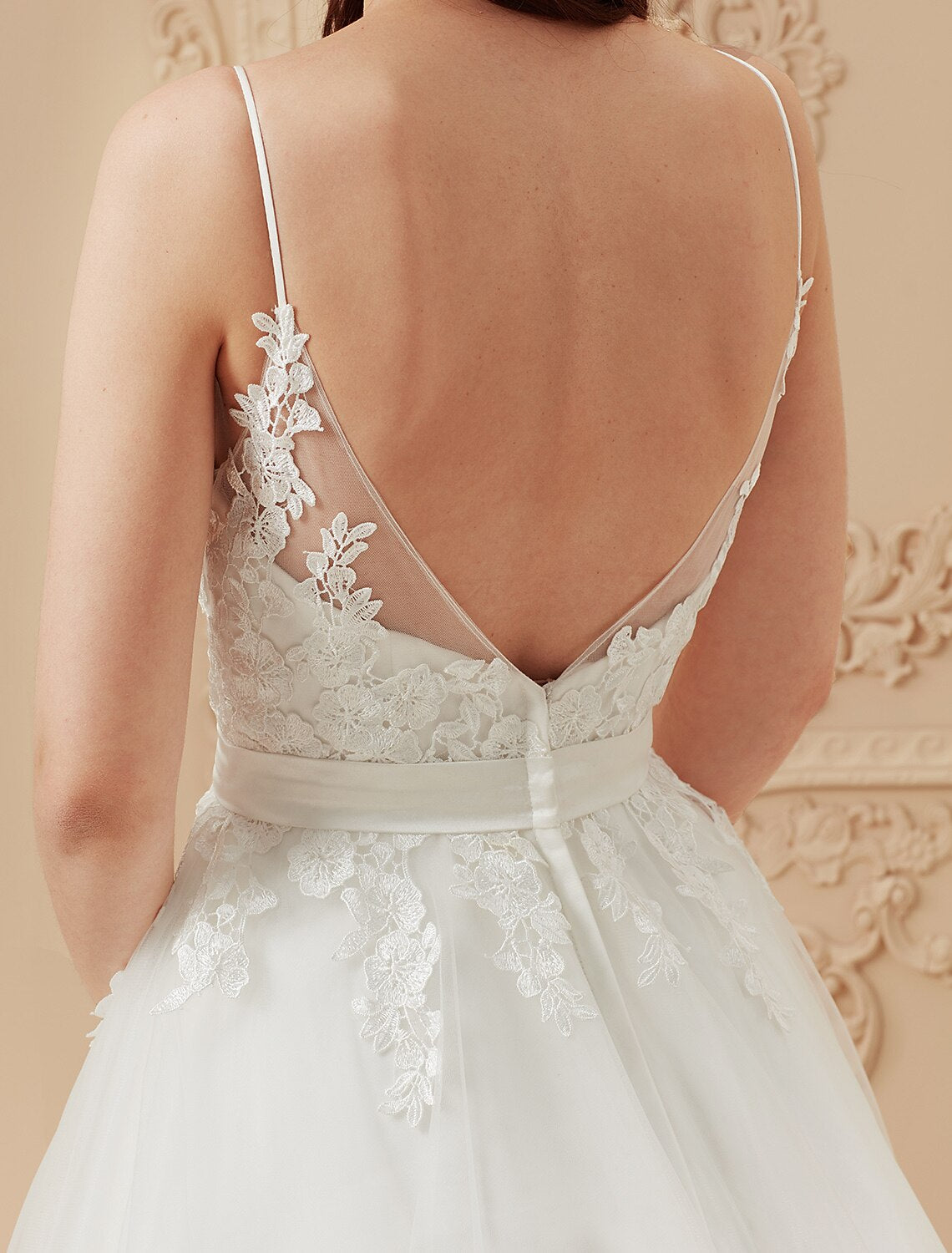 Close-up of the delicate lace appliques and ruffled details on a wedding dress.