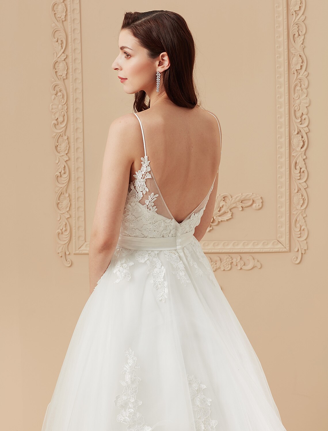 Full length view of a V-neck spaghetti strap bridal gown with a flowing train.
