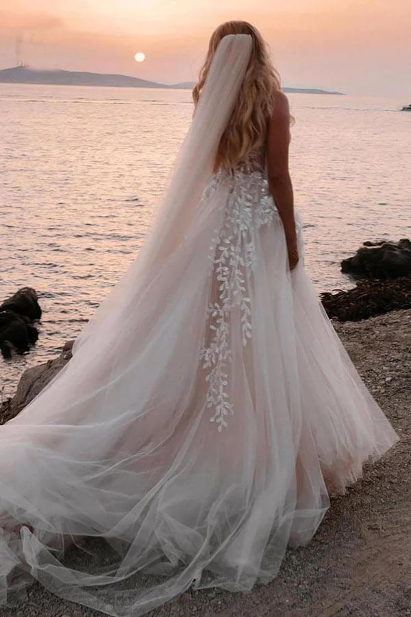 Close-up of sweetheart neckline and delicate lace appliques on wedding dress.