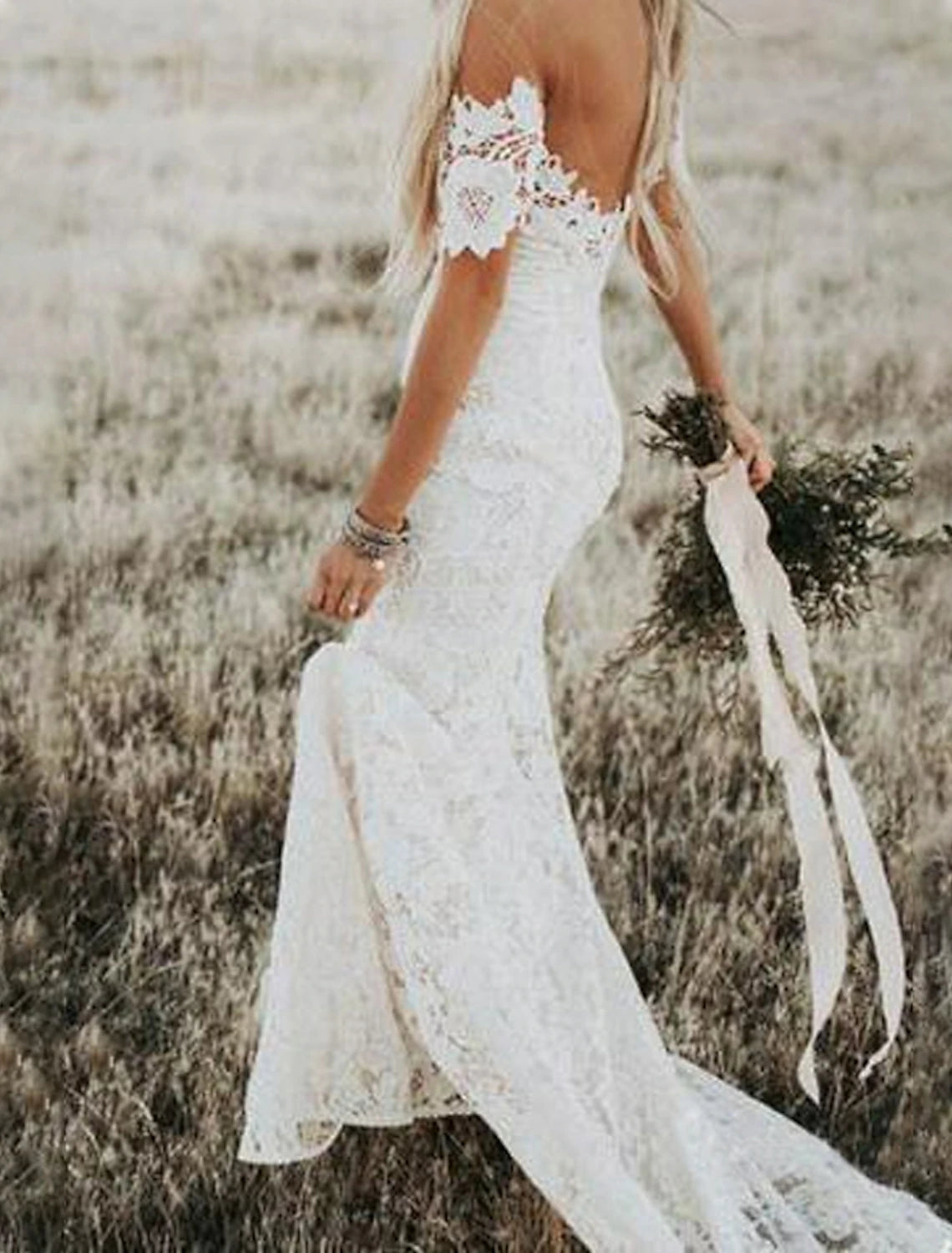 Full length view of a trumpet silhouette wedding dress with off-shoulder neckline.