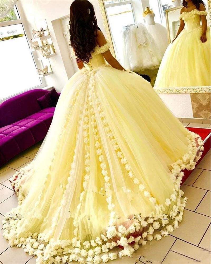 Pale yellow off-shoulder ball gown with floral trim and tulle skirt.