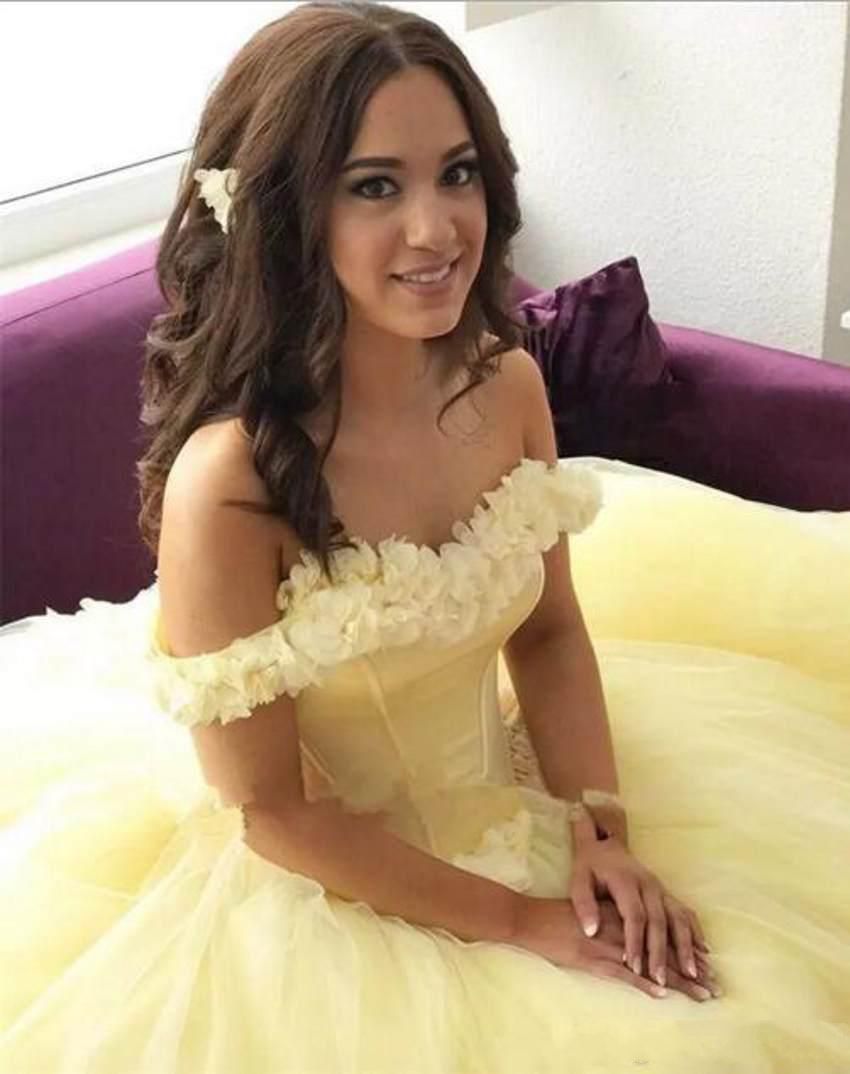Model wearing a romantic pale yellow off-shoulder floral ball gown.