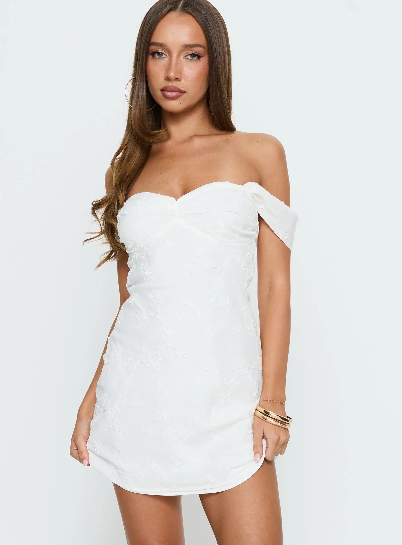 Close-up of floral appliqué on white off-shoulder dress fabric.