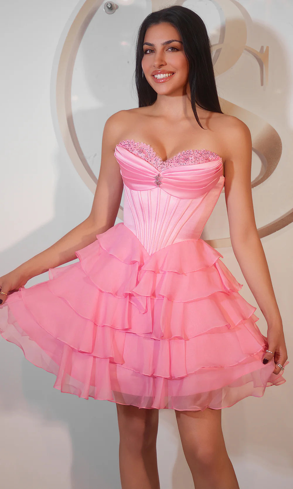 Model wearing a lavender strapless sweetheart corset mini homecoming dress with tiered tulle skirt and rhinestone accent.