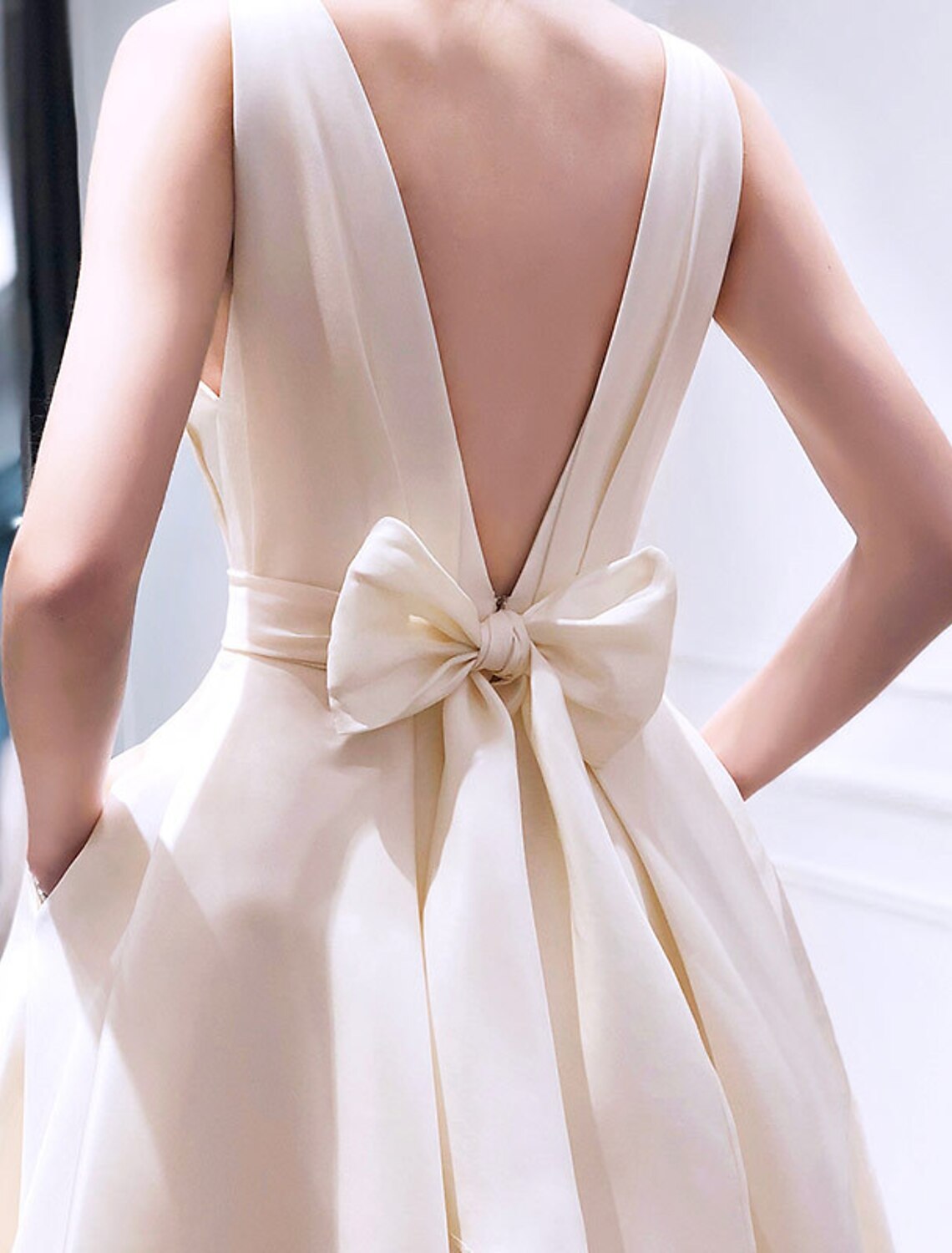 Back view of a woman in a champagne short fitted party dress.