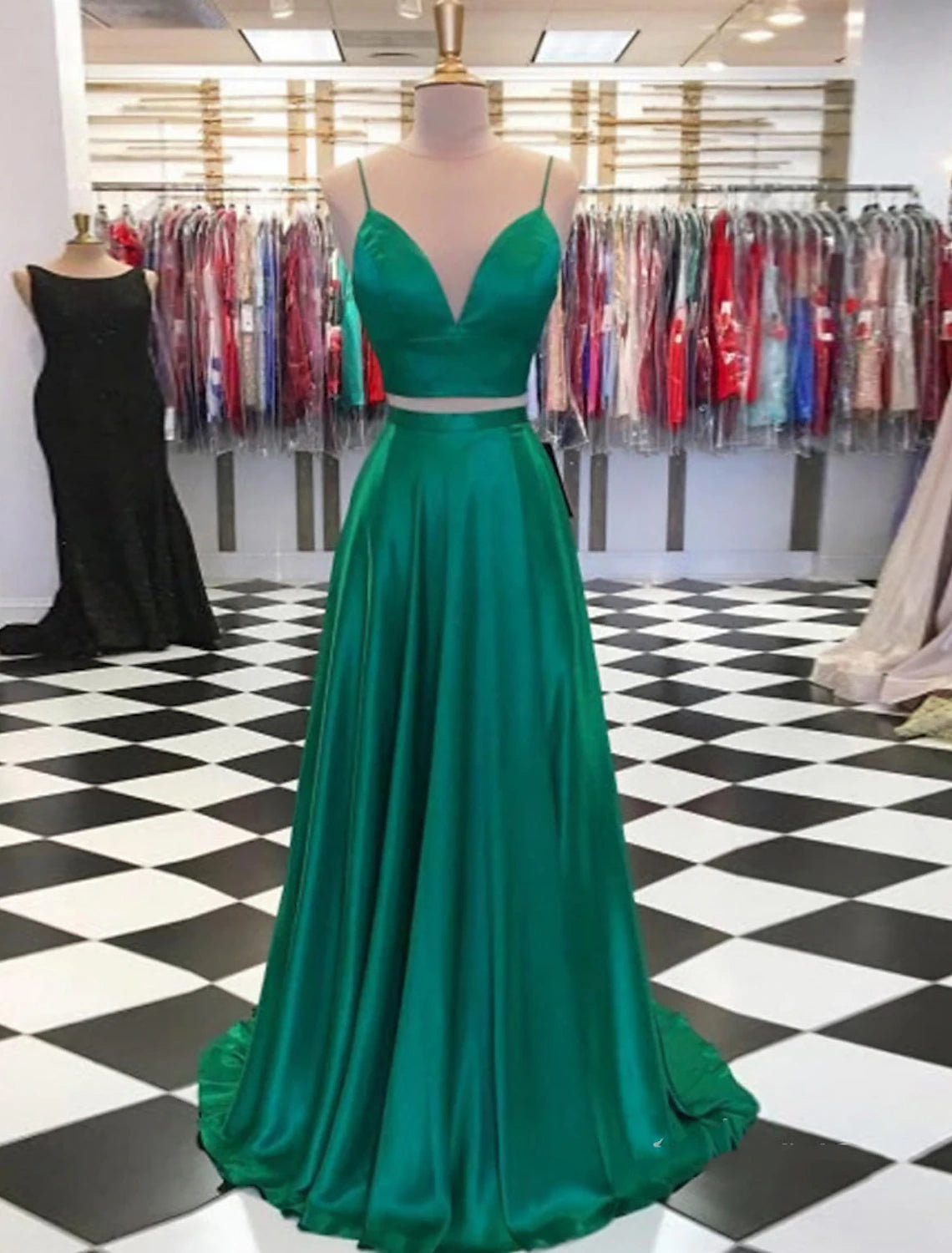 Model wearing a two-piece charmeuse prom dress with spaghetti straps and a high slit.