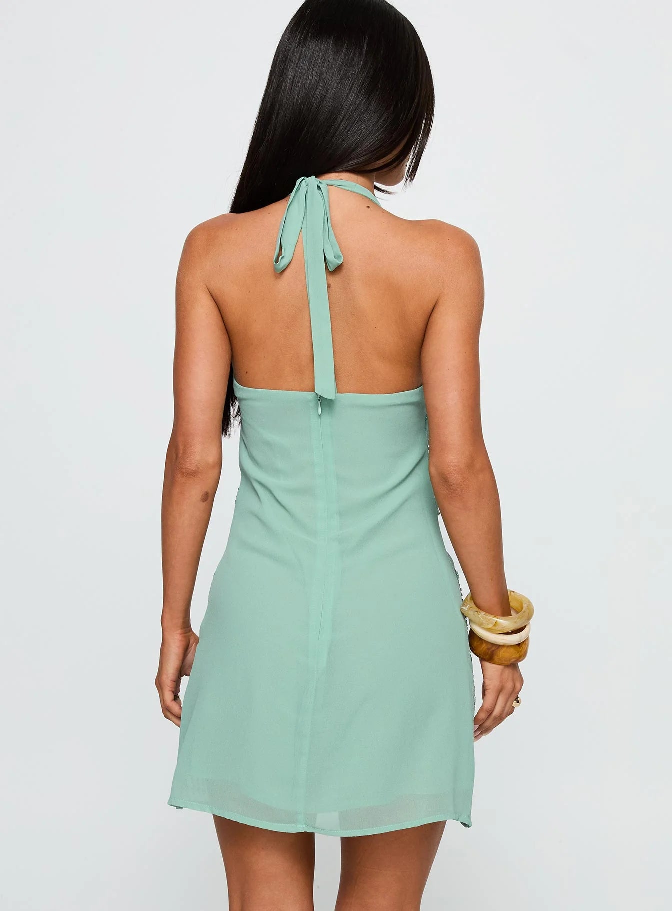 Close-up of the sequin embellishments and keyhole detail on the sage green halter dress.