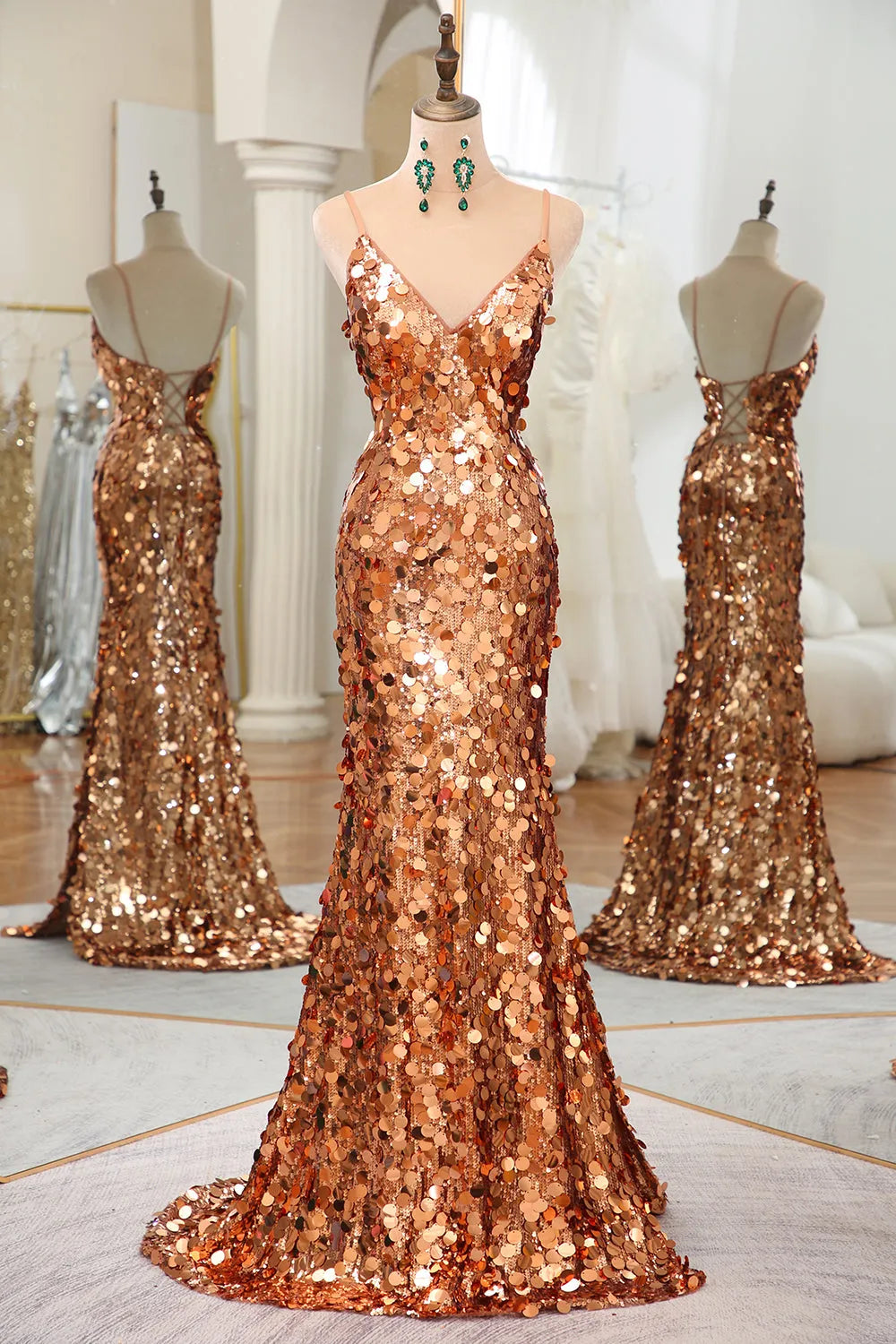 Woman wearing a rose gold sequin mermaid prom dress with spaghetti straps and a high leg split.