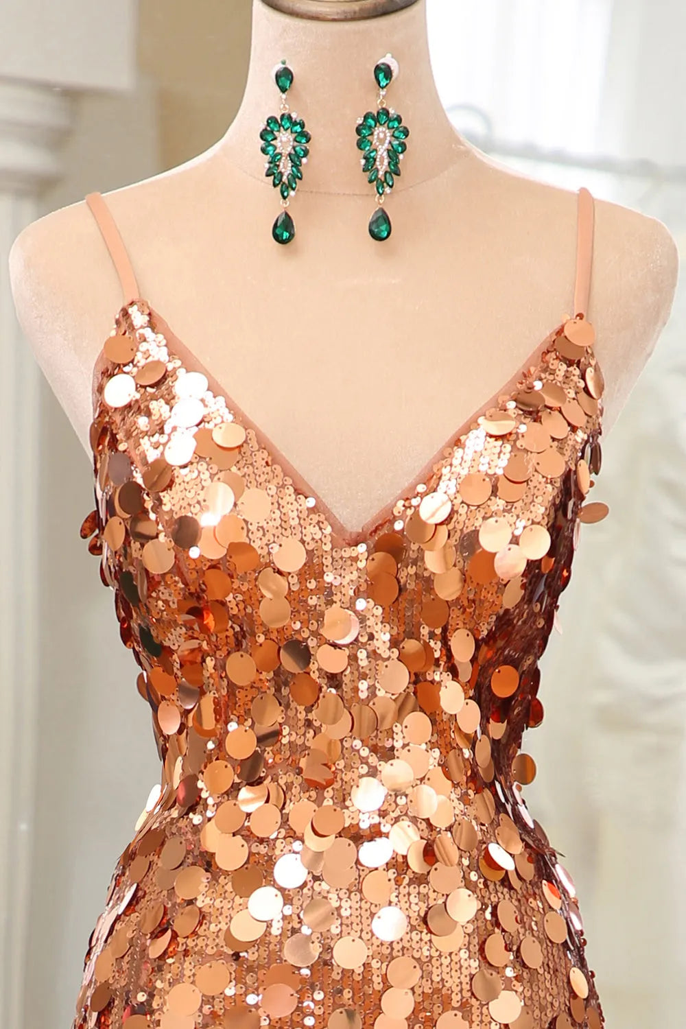 Woman posing in a rose gold sequin mermaid dress, highlighting the spaghetti straps and split.
