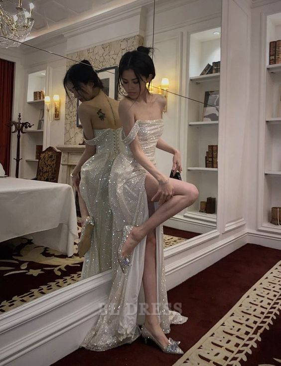 Woman wearing a shimmering one-shoulder mermaid prom dress with a high slit.