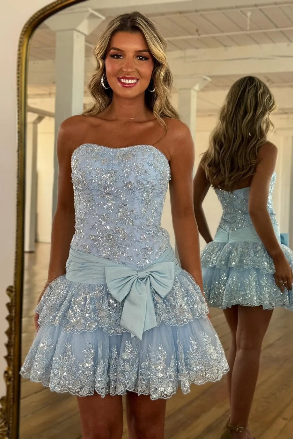 Light blue strapless homecoming dress with lace sequins, tiered skirt, and bow waist.