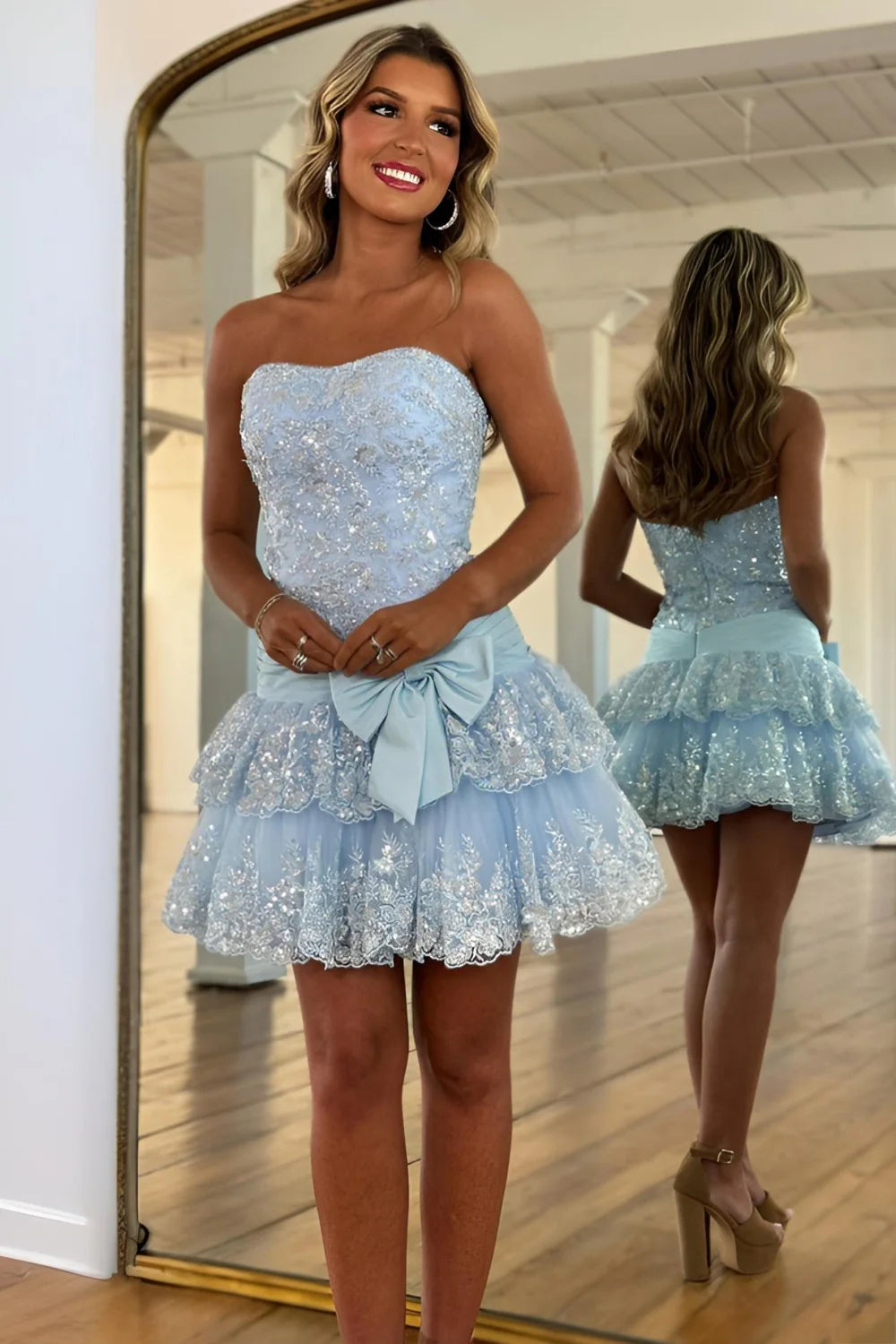 Back view of light blue strapless homecoming dress showing tiered skirt and bow detail.