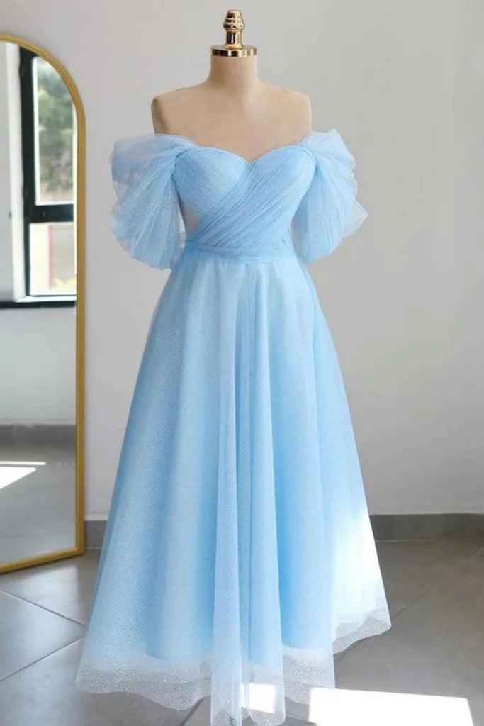 Model wearing a shiny off-the-shoulder tulle tea-length homecoming dress.