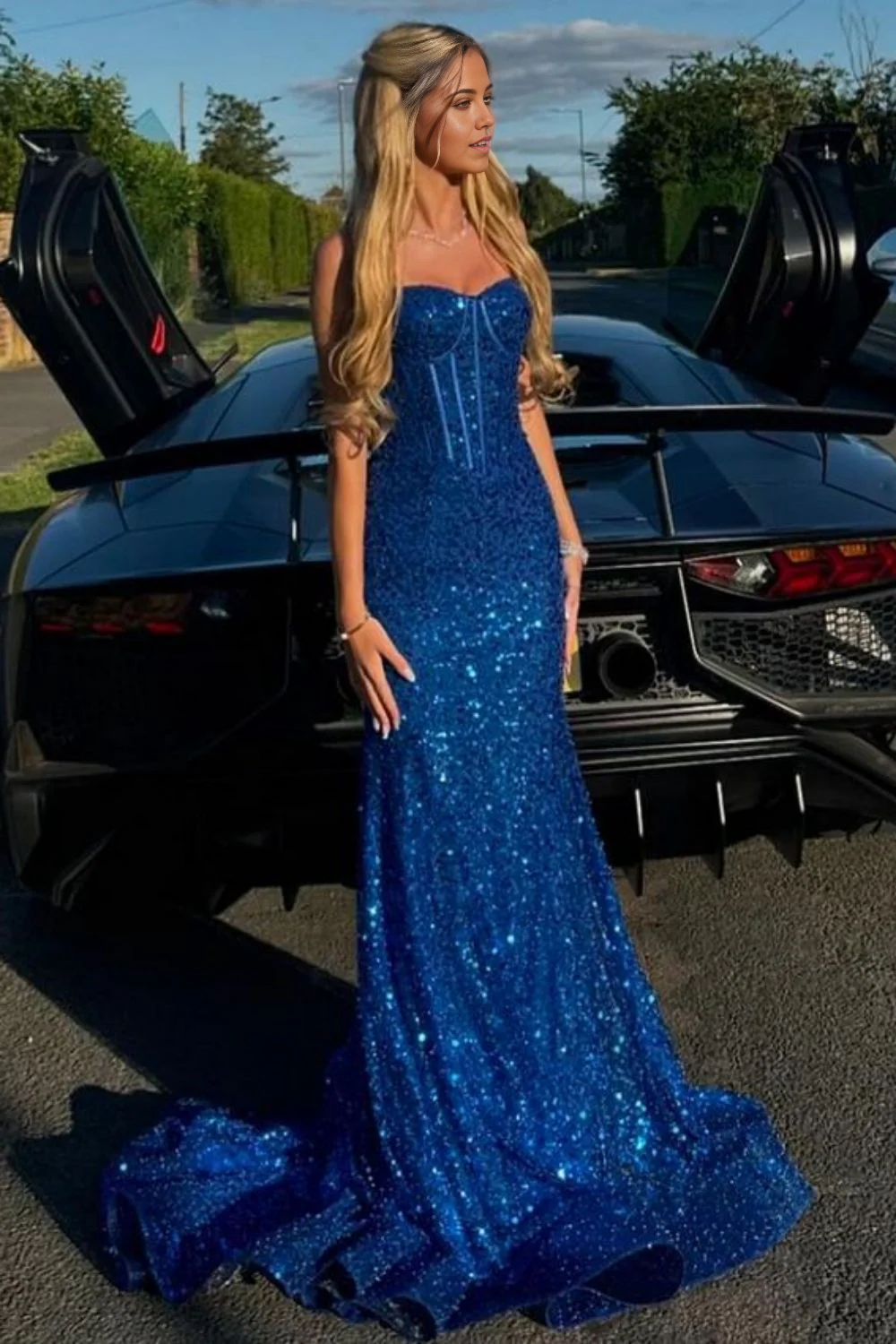 Back view of a model in a light blue mermaid prom dress with spaghetti straps.