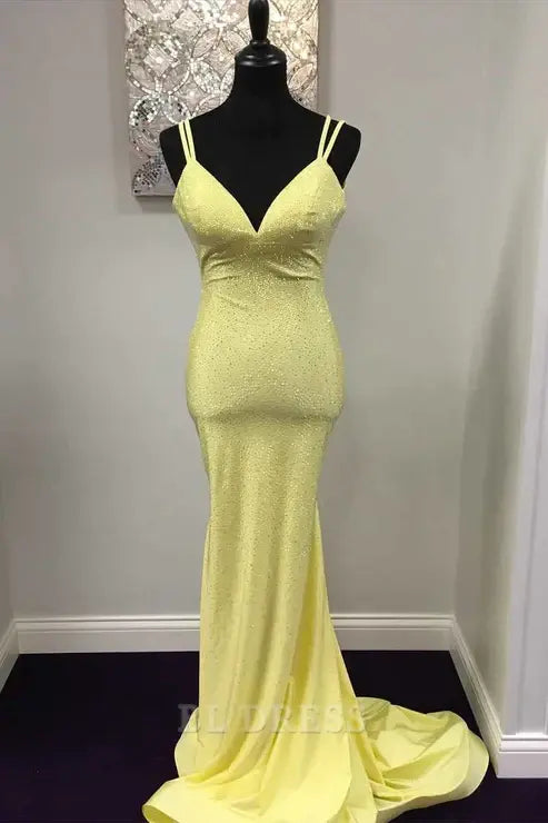 Woman wearing a yellow shiny mermaid formal dress with V-neck and backless design.