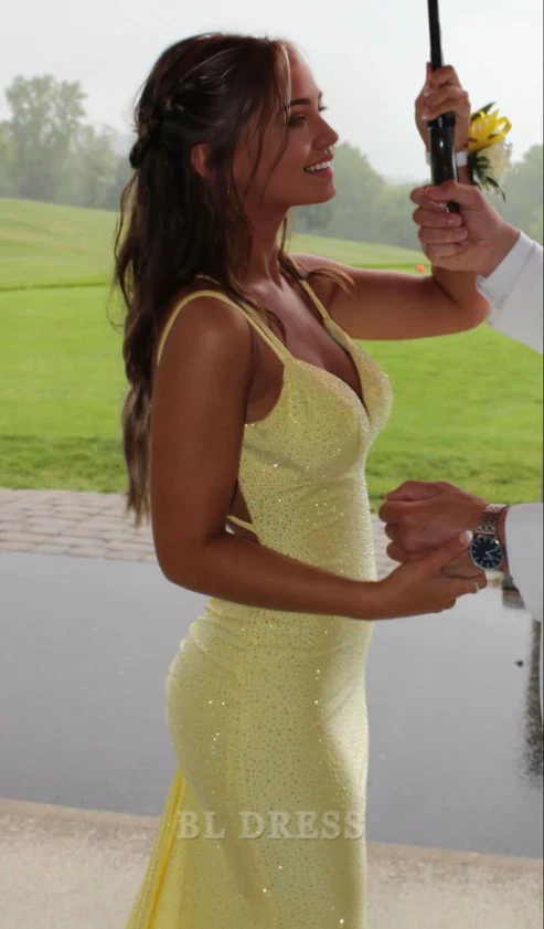 Full-length view of a woman in a yellow shiny mermaid evening gown.